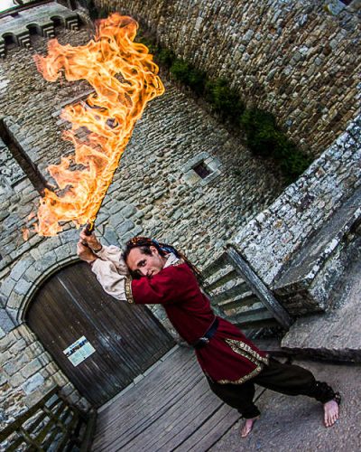 Kum-Kum en costume médiéval avec torche enflammée — spectacle de feu médiéval en rue